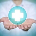 Close-up man in white shirt holding white first aid icon.